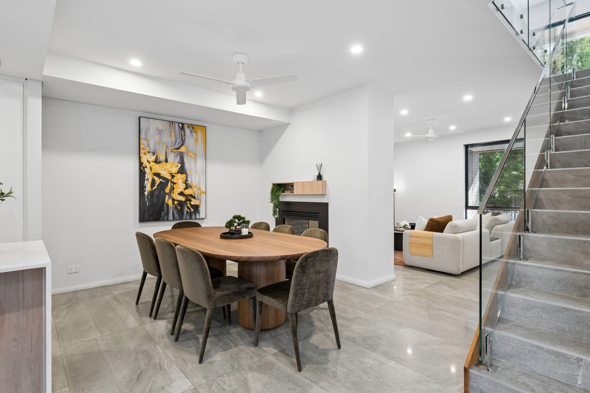 Dining room with oval timber table, velvet chairs and framed artwork