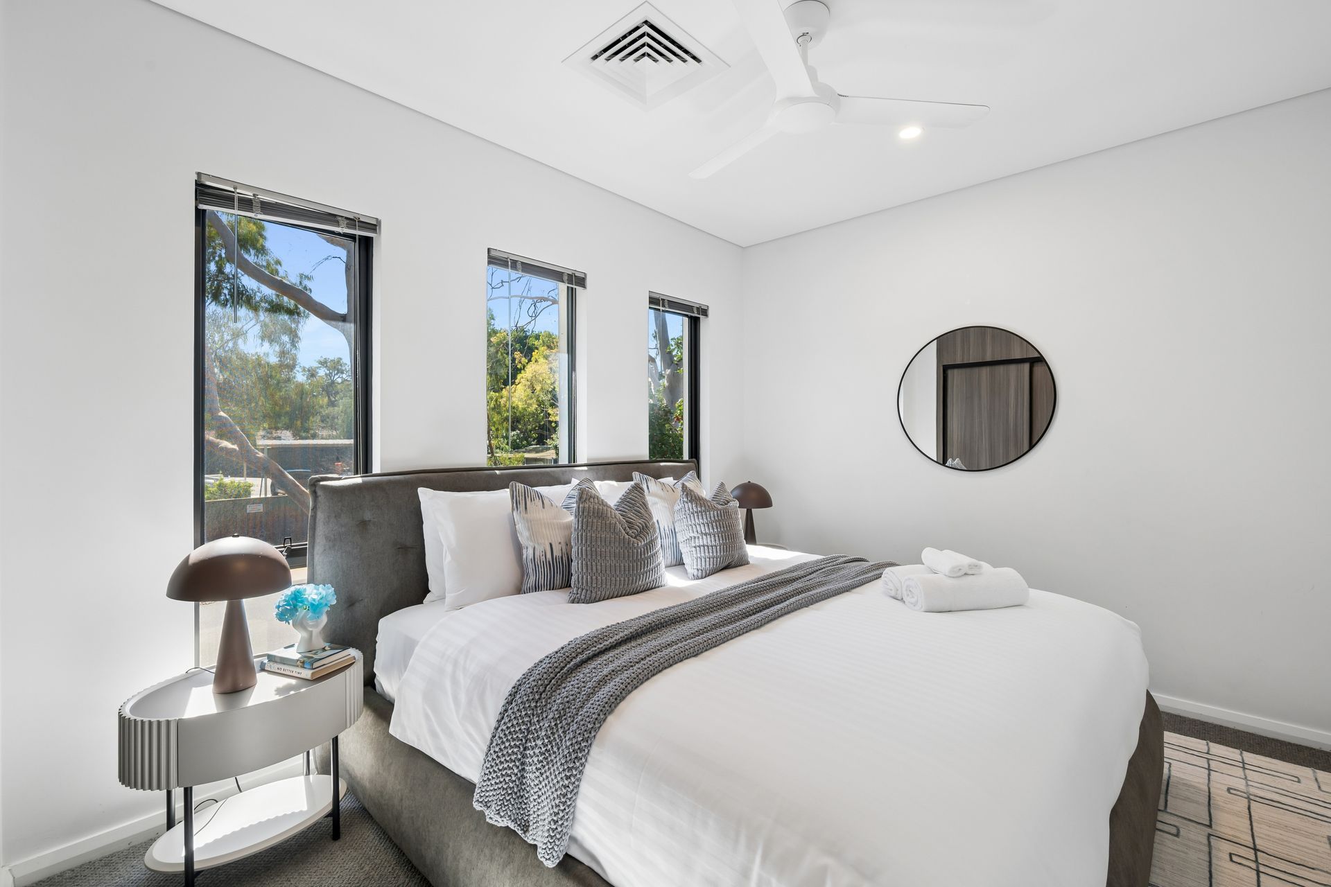 Styled guest bedroom with upholstered bedhead, linen and bedside lighting