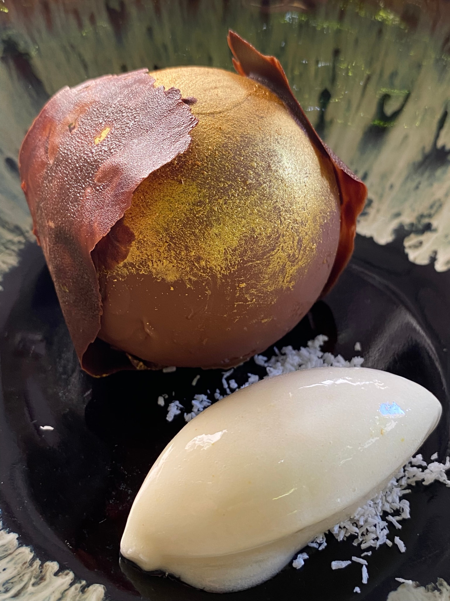 Gold-dusted chocolate sphere dessert with coconut sorbet